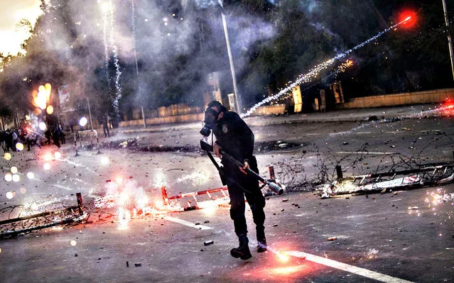 Egyptian students who support the Muslim Brotherhood (background) shoot fireworks at riot policemen (foreground) during clashes outside the University of Cairo campus in the capital on December 11, 2013. (Photo by Mahmoud Khaled/AFP Photo)