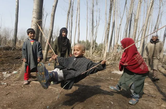 Kashmiri children play on a swing made from rope, on the outskirts of Srinagar, the summer capital of Indian Kashmir, 18 February 2016. The temperature in the Kashmir valley has risen and people are out enjoying the warmer weather. (Photo by Farooq Khan/EPA)