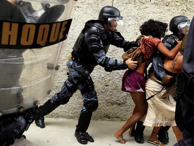 Police officers clash with supporters of the native Indian community during a protest outside the Indian museum, next to the Maracana stadium, in Rio de Janeiro, on December 16, 2013. Police arrested more than 20 indigenous people who occupied the abandoned museum as a protest against its demolition as part of renovations ahead of the 2014 World Cup, to be played in Brazil. (Photo by Pilar Olivares/Reuters)