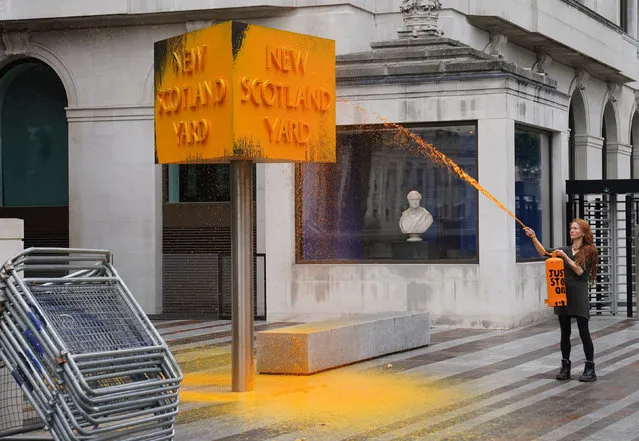 A Just Stop Oil protester spray paints a sign outside New Scotland Yard in London on Friday, October 14, 2022. (Photo by Stefan Rousseau/PA Images via Getty Images)