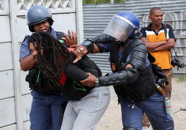 Police officers detain a resident at Oasis Farm informal settlement in Philippi during clashes with authorities as they clamp down on illegal electricity connections in the area, in Cape Town, South Africa on December 12, 2023. (Photo by Esa Alexander/Reuters)