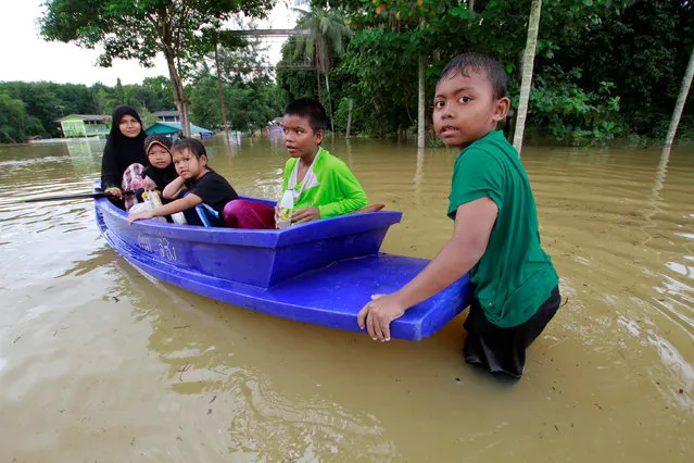 Thai Muslim villagers sit on a boat as a boy pushes it through a flooded street in Yala province, southern Thailand, January 21, 2017. (Photo by Surapan Boonthanom/Reuters)