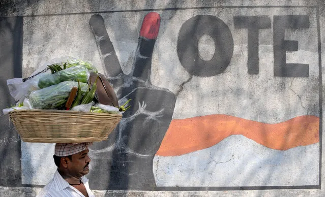 A vegetable vendor walks past graffiti urging Indians to vote, in Mumbai on February 3, 2017. Five Indian states representing more than 160 million voters will go to the polls, a key test for the prime minister after his shock currency move. The elections will begin on February 4, nearly three months after Modi announced he was scrapping nearly 86 percent of all Indian currency, a move aimed at curbing widespread tax evasion. (Photo by Indranil Mukherjee/AFP Photo)