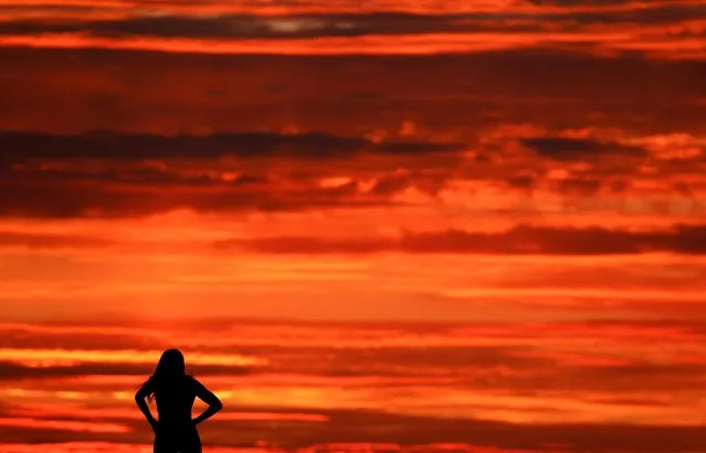 A woman looks at the sunset over the port of Portivy in Saint-Pierre-Quiberon, Brittany, France, October 9, 2021. (Photo by Pascal Rossignol/Reuters)