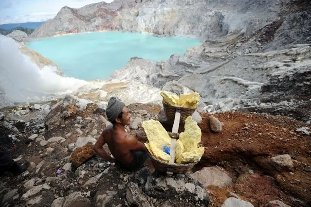 This Photo taken on February 1, 2014 shows a miner carrying blocks of sulphur from Ijen crater in Banyuwangi East Java. A miner can weigh from 45 to 90kg and might make as many as two or three trips in a day. The sulfur is then used for vulcanizing rubber, bleaching sugar and other industrial processes. (Photo by Sonny Tumbelaka/AFP Photo)