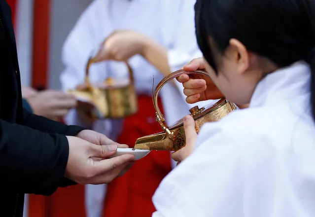 People receives a sacred sake from Shinto maidens as a ritual after a ceremony for companies wishing for prosperous business at the start of the new business year at Kanda Myojin Shrine, which is known to be frequented by worshippers seeking good luck and prosperous businesses. in Tokyo, Japan, January 4, 2017. (Photo by Toru Hanai/Reuters)