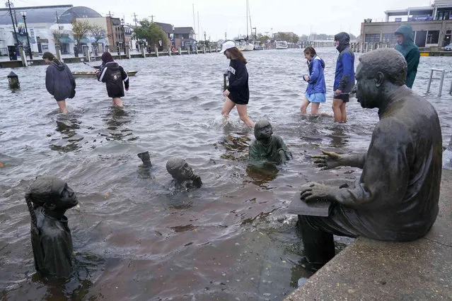 People walk past the Kunta Kinte-Alex Haley Memorial as they survey the flooding in downtown Annapolis, Friday, October 29, 2021. The city is anticipating potential historic tidal flooding conditions in low-lying areas Friday and Saturday. (Photo by Susan Walsh/AP Photo)