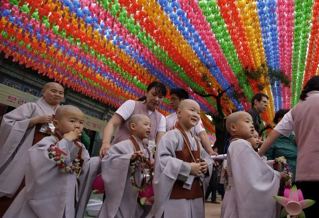 Boys with newly shaved heads walk under colorful lanterns after a service to celebrate Buddha's upcoming birthday at Jogye Temple in Seoul, South Korea Monday, May 11, 2015. Nine children entered the temple to have an experience of monks' life for two weeks. (Photo by Lee Jin-man/AP Photo)