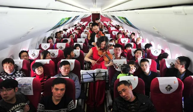 Musicians play violins during a spring concert for passengers on an airplane from Kunming to Hangzhou on January 31, 2016 in Kunming, Yunnan Province of China. (Photo by ChinaFotoPress via Getty Images)