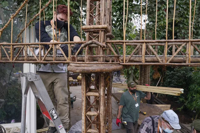 Kieran Beam, left, works on the train tracks as part of the preparations for the annual Holiday Train Show at the New York Botanical Garden in New York, Thursday, November 11, 2021. The show, which opens to the public next weekend, features model trains running through and around New York landmarks, recreated in miniature with natural materials. (Photo by Seth Wenig/AP Photo)