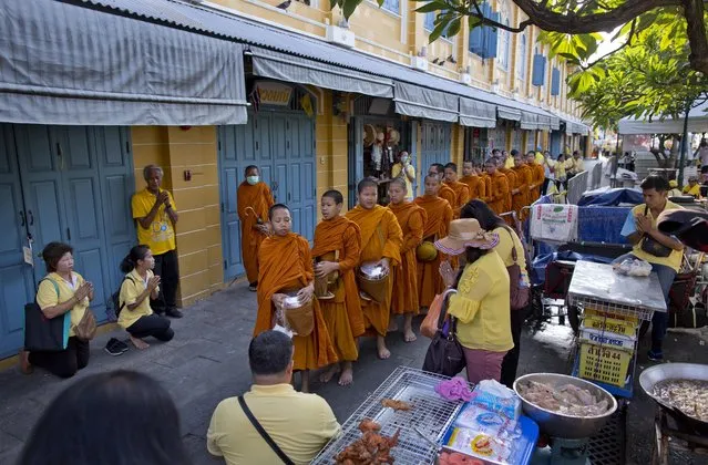 Thai people make offerings to Buddhist monks who collect alms close to The Grand Palace in which King Maha Vajiralongkorn's coronation takes place on Sunday, May 5, 2019, in Bangkok, Thailand. King Maha Vajiralongkorn was officially crowned amid the splendor of the country's Grand Palace, taking the central role in an elaborate centuries-old royal ceremony that was last held almost seven decades ago. (Photo by Gemunu Amarasinghe/AP Photo)