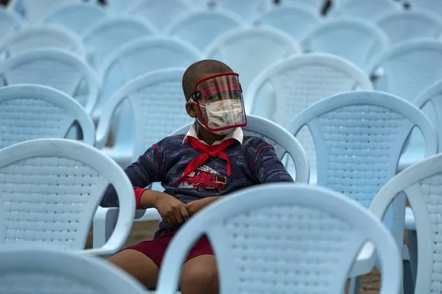 A student wearing a mask as a precaution amid the spread of COVID-19 wait during the official opening ceremony of the school year in Havana, Cuba, Monday, November 15, 2021. After 20 months of strict quarantine rules that included limiting foreign travel to the island, Cuba today reopens to the world. Airports, hotels, businesses and the remaining half of the student population resume activities. (Photo by Ramon Epinosa/AP Photo)