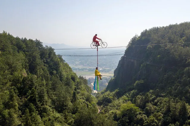 Men perform high-wire stunts on a tightrope in the Shiniuzhai national geological park in Yueyang, Hunan province, China on June 4, 2019. (Photo by Reuters/China Stringer Network)