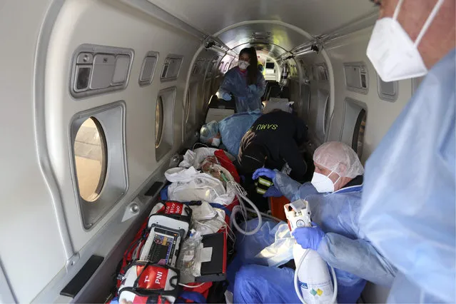 Paramedics, nurses and doctors tend to a coronavirus (Covid-19) affected patient inside a medical aircraft during a transfer ahead of flying from Bastia on the French Mediterranean island of Corsica to the city of Brest, western France, on January 5, 2022. (Photo by Pascal Pochard-Casabianca/AFP Photo)