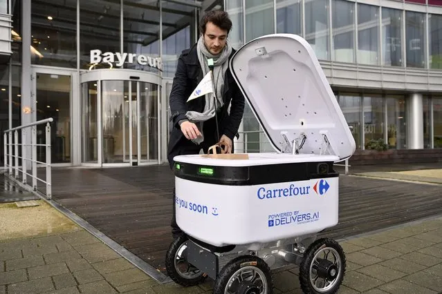 A man receives an order during a test run of an autonomous delivery robot provided with artificial intelligence in Zaventem on January 16, 2023. (Photo by Eric Lalmand/BELGA via AFP Photo)