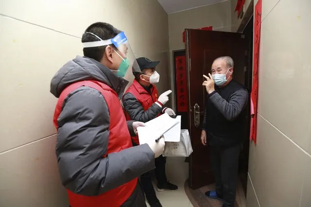 Community volunteers visit residents to find out their needs at a residential block in Xi'an city in northwest China's Shaanxi province Monday, January 3, 2022. (Photo by Chinatopix via AP Photo)