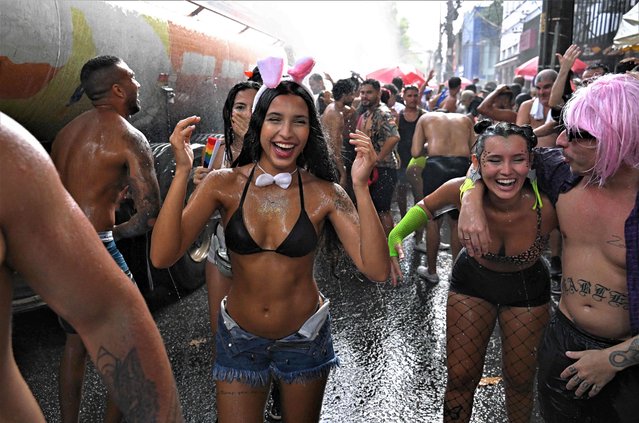 Revellers are sprayed by a water cannon during a street party called “Bloco Das Barbas” in Rio de Janeiro, Brazil on February 18, 2023. Hundreds of street parties traditionally take place every year in the city before and during Rio de Janeiro's carnival. (Photo by Carl de Souza/AFP Photo)