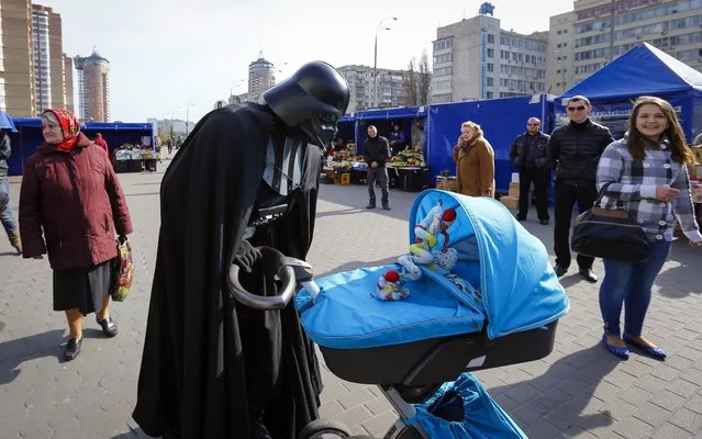 “Darth Vader”, the leader of the Internet Party of Ukraine, looks at a child in a pram at a street market near the Ukrainian Central Elections Commission in Kiev April 3, 2014. “Darth Vader” has submitted documents to the Ukrainian Central Elections Commission to register as a candidate for Ukraine's May 25 presidential election. (Photo by Shamil Zhumatov/Reuters)