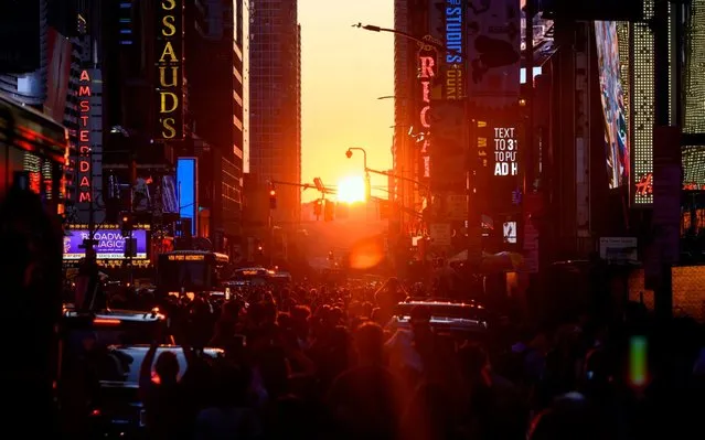 People take pictures of the sun setting over Manhattan on 42nd Street during the so called “Manhattanhenge” on July 12, 2019 in New York City. Manhattanhenge happens four times each year, when when the sun rises or sets in New York City parallel to the city street grid in Manhattan. (Photo by Johannes Eisele/AFP Photo)