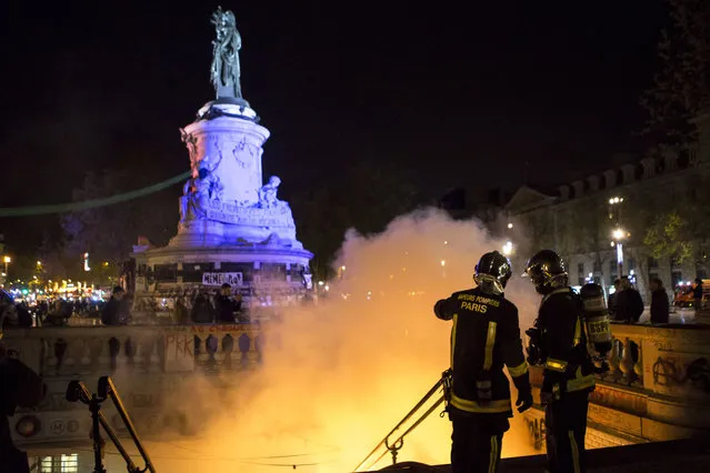 Firefighters stand next an entrance of a subway station set on fire by demonstrators gathered on the Place de la Republique in Paris, France, Sunday, May 1st, 2016. Fearing France's worker protections are under threat, hundreds of angry youths on the sidelines of a May Day labor rally hurled stones and wood at police in Paris, receiving repeated bursts of tear gas in response. (Photo by Kamil Zihnioglu/AP Photo)