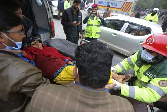 Rescue workers evacuate an injured woman from the site of a bomb explosion, in Lahore, Pakistan, Thursday, January 20, 2022. Police said the powerful bomb exploded in a crowded bazar in Pakistan's second largest city of Lahore, killing several people and wounding dozens of others. (Photo by K.M. Chaudary/AP Photo)