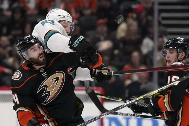 Anaheim Ducks center Adam Henrique, left, and San Jose Sharks defenseman Nicolas Meloche, center, reach for the puck as right wing Troy Terry watches during the third period of an NHL hockey game Sunday, March 6, 2022, in Anaheim, Calif. (Photo by Mark J. Terrill/AP Photo)