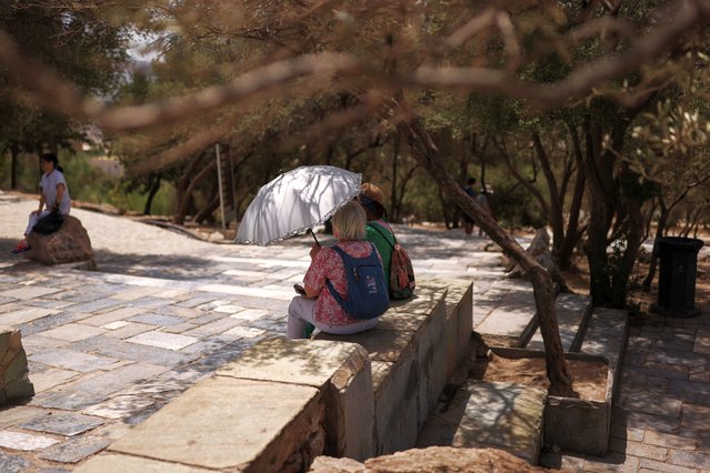 A woman holds an umbrella at the Acropolis hill archaeological site, as a heatwave hits Athens, Greece, on June 12, 2024. (Photo by Stelios Misinas/Reuters)