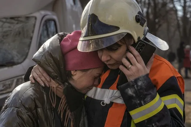 A firefighter comforts a woman outside a destroyed apartment building after a bombing in a residential area in Kyiv, Ukraine, Tuesday, March 15, 2022. (Photo by Vadim Ghirda/AP Photo)