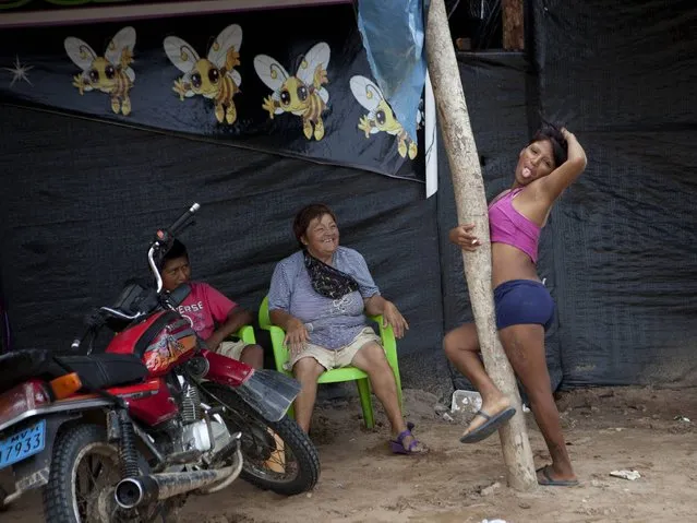 A s*x worker who is employed by an informal bar playfully sticks out her tongue while posing for a photo, outside her place of her employment in La Pampa in Peru's Madre de Dios region. Since artisanal gold mining took hold in La Pampa, miners began carving a lawless, series of ramshackle settlement out of the Amazonian jungle territory in 2008. (Photo by Rodrigo Abd/AP Photo)