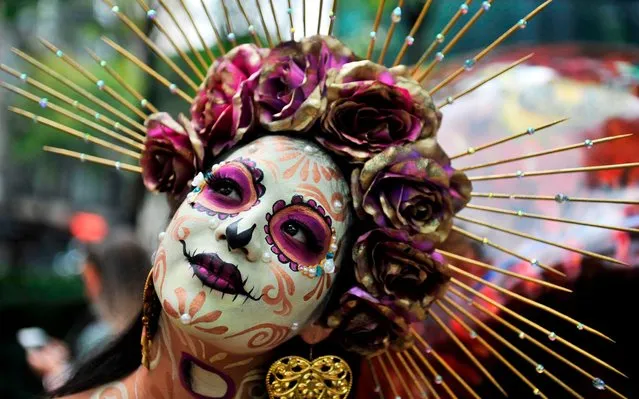 A woman fancy dressed as Catrina takes part in the “Catrinas Parade” along Reforma Avenue, in Mexico City on October 26, 2019. Mexicans get ready to celebrate the Day of the Dead highlighting the character of La Catrina which was created by cartoonist Jose Guadalupe Posada, famous for his drawings of typical local, folkloric scenes, socio-political criticism and for his illustrations of “skeletons” or skulls, including La Catrina. (Photo by Claudio Cruz/AFP Photo)