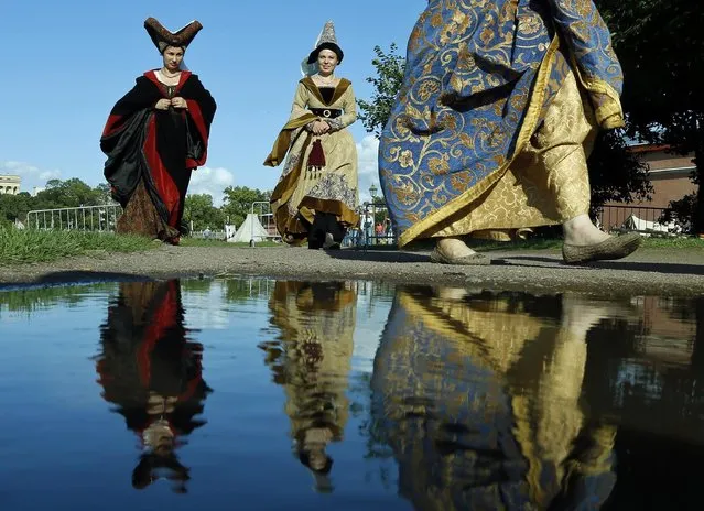 Members of medieval knights historical clubs are reflected in the water as they walk to the venue during a historical festival in St.Petersburg, Russia, Sunday, July 19, 2015. (Photo by Dmitry Lovetsky/AP Photo)