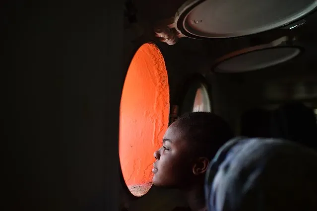 A woman looks through a window of rescue ship “Aquarius” as more the 380 migrants arrive in the port of Cagliari, Sardinia, on May 26, 2016, two days after being rescued near the Libyan coasts. The Aquarius is a former North Atlantic fisheries protection ship now used by humanitarians SOS Mediterranee and Medecins Sans Frontieres (Doctors without Borders) which patrols to rescue migrants and refugees trying to reach Europe crossing the Mediterranean sea aboard rubber boats or old fishing boat. (Photo by Gabriel Bouys/AFP Photo)