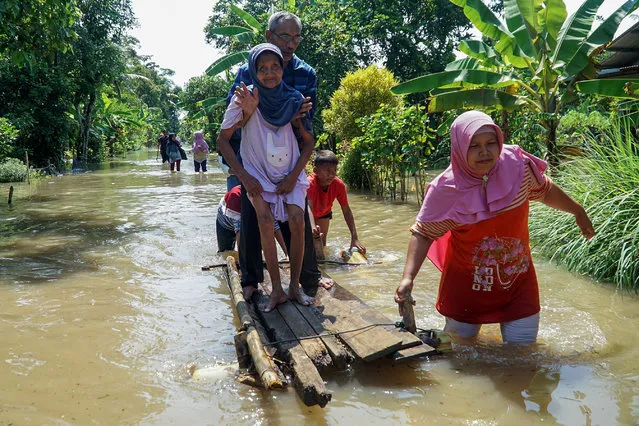 A woman pulls a wooden craft carrying her family in flood water after attending a wedding ceremony in Cilacap, Central Java, Indonesia, March 16, 2022. (Photo by Xinhua News Agency/Rex Features/Shutterstock)