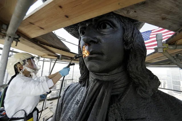 Eliot Bassett-Cann, with Moorland Studios Inc., applies a protective coating to the sculpture of William Penn atop City Hall, Thursday, June 1, 2017, in Philadelphia. The 37-foot bronze sculpture by Alexander Milne Calder has been atop City Hall for 125 years. The sculpture's conservation project happens every ten years and takes four to five weeks to complete. (Photo by Matt Slocum/AP Photo)