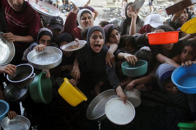 Palestinians react as they wait to receive food cooked by a charity kitchen, amid a hunger crisis as conflict between Israel and Hamas continues, in the northern Gaza Strip on August 14, 2024. (Photo by Mahmoud Issa/Reuters)