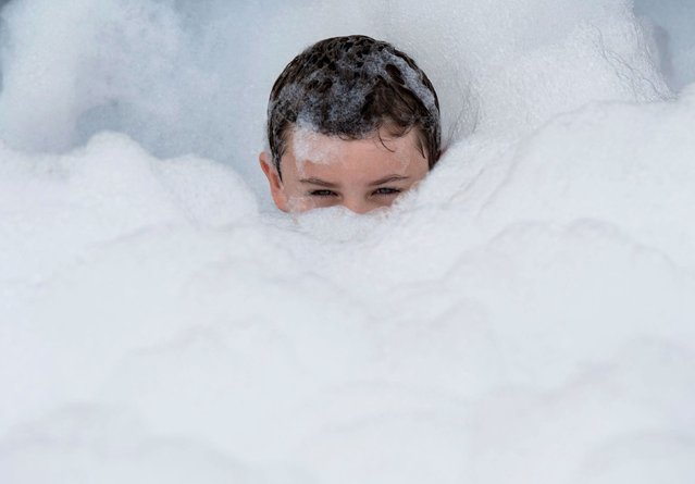 Emmett Quinto, 7, plays in a bubble station set up for children at the Woodward Dream Cruise, an automotive event in Ferndale, Michigan, on Saturday, August 17, 2024. (Photo by David Rodriguez Munoz/Detroit Free Press via USA Today Network)