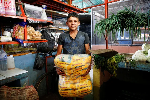 Carlos Cure holds packets of corn flour made in Colombia as he poses for a picture at a stall that sells food and staple items at a market in La Fria, Venezuela, June 2, 2016. (Photo by Carlos Garcia Rawlins/Reuters)