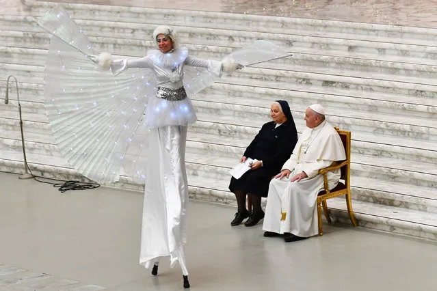Pope Francis and Suor Antonietta Collacchi, director of the Santa Marta dispensary, look at a performer on stilts during an audience for children and families of the Santa Marta dispensary on December 22, 2019 at Paul-VI hall in the Vatican. (Photo by Vincenzo Pinto/AFP Photo)