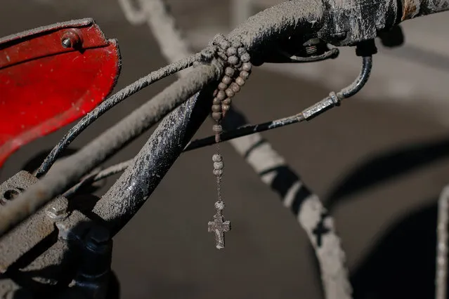 A view of a Rosary hanging from a motorcycle covered in volcanic ash in Talisay, Batangas, Philippines, 14 January 2020. Thousands of people have been ordered to evacuate as authorities in the Philippines raised the alert status of the Taal Volcano, which started spewing lava on 13 January. Ashfall has covered nearby communities and has also reached Manila, located 70 kilometers away. (Photo by Mark R. Cristino/EPA/EFE)