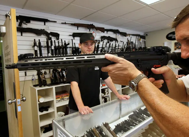 A prospective buyer examines an AR-15 as salesman Ryan Martinex watches at the “Ready Gunner” gun store in Provo, Utah, U.S., June 21, 2016. (Photo by George Frey/Reuters)