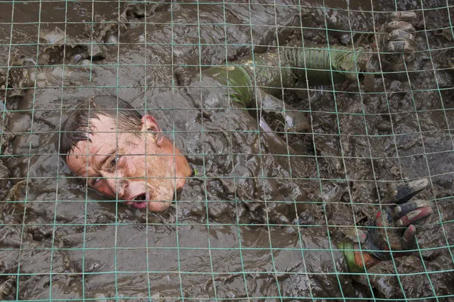 A participant crawls through the mud during the Race of Heroes event at Koltsovo training ground in Novosibirsk, Russia on July 3, 2016. (Photo by Kirill Kukhmar/TASS via Getty Images)
