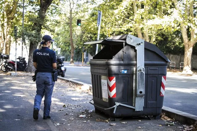An Italian police officer walks past the site where a trash bin was removed after two amputated legs were found in Rome, Wednesday, August 16, 2017. According to the Italian Police first investigations the part of the human body found belongs to a woman. (Photo by Angelo Carconi/ANSA via AP Photo)