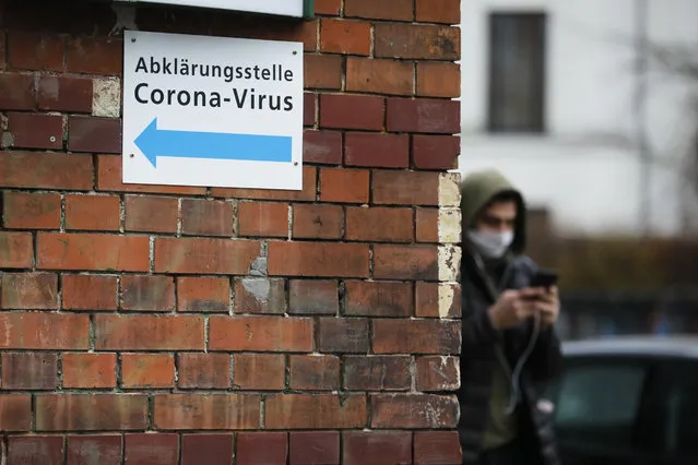 A man with a mask pass an information sign directing to a new set up test and information centre for the new coronavirus at the district Prenzlauer Berg in Berlin, Germany, Monday, March 9, 2020. (Photo by Markus Schreiber/AP Photo)