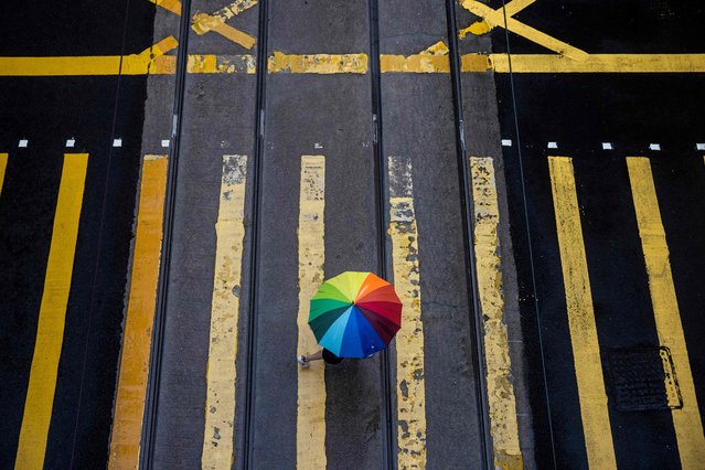 A pedestrian holding an umbrella crosses a street during a day of heavy rain in Hong Kong on June 8, 2022. (Photo by Isaac Lawrence/AFP Photo)