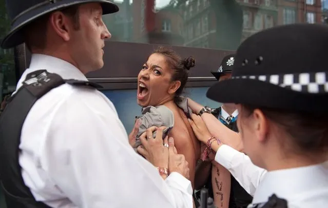 British policemen block a topless activist of Ukraine's prominent feminist rights group FEMEN as she was protesting near the Tower Bridge in Central London on August 2, 2012 on day 6 of the London 2012 Olympic games. FEMEN's activists organised an “islamic maraton” to demonstrate against “islamic regimes” they say being supported by the International Olympic Committee. (Photo by Will Oliver/AP Photo)