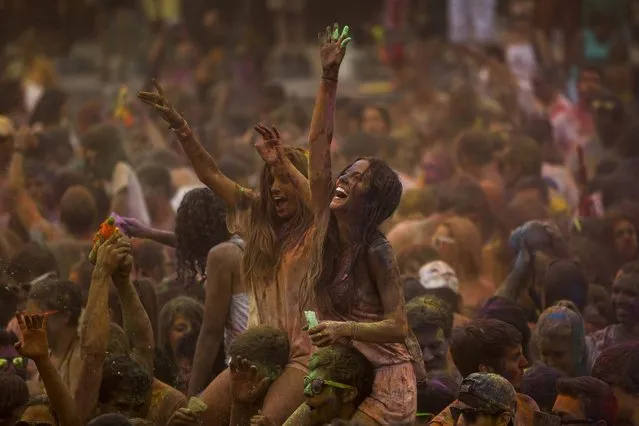 Revelers dance after throwing special colored powders on each other during a Monsoon Holi Festival in Madrid, Spain, Saturday, August 9, 2014. The festival is based on the Hindu spring festival Holi, also known as the festival of colors where participants color each other with dry powder and colored water. (Photo by Andres Kudacki/AP Photo)
