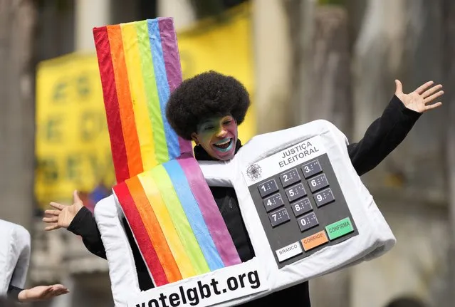 An LGBT activist wearing a costume in the likeness of an electronic voting machine gathers with others after the reading of two manifestos defending the nation's democratic institutions and electronic voting system outside the Faculty of Law at Sao Paulo University in Sao Paulo, Brazil, Thursday, August 11, 2022. The two documents are inspired by the original “Letter to the Brazilians” from 1977 denouncing the brutal military dictatorship and calling for a prompt return of the rule of law. (Photo by Andre Penner/AP Photo)
