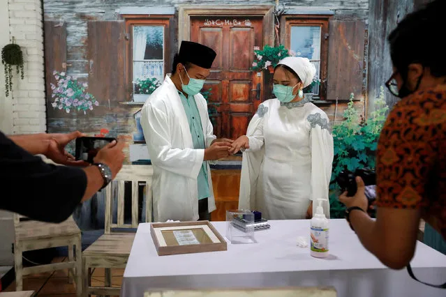 Mohamad Nurjaman, a 31-year-old groom, puts on the ring on Ugi Lestari Widya Bahri, the 24-year-old bride, during their wedding ceremony amid the spread of coronavirus disease (COVID-19), in Tangerang, on the outskirts of Jakarta, Indonesia, April 10, 2020. (Photo by Willy Kurniawan/Reuters)