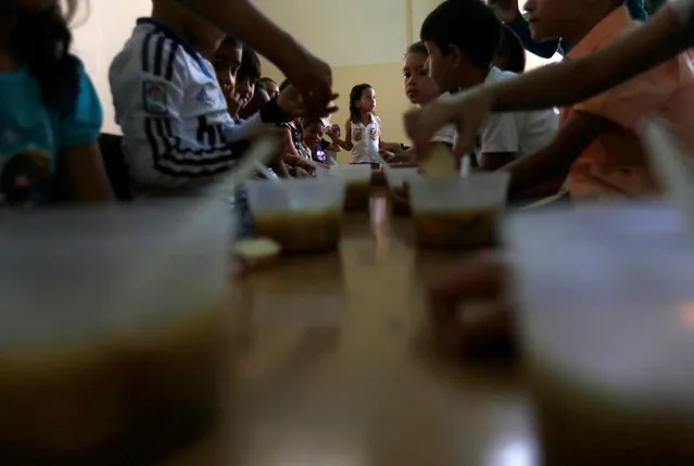 A student waits to be served as her classmates enjoy a soup cooked for them during an activity for the end of the school year at the Padre Jose Maria Velaz school in Caracas, Venezuela July 12, 2016. (Photo by Carlos Jasso/Reuters)