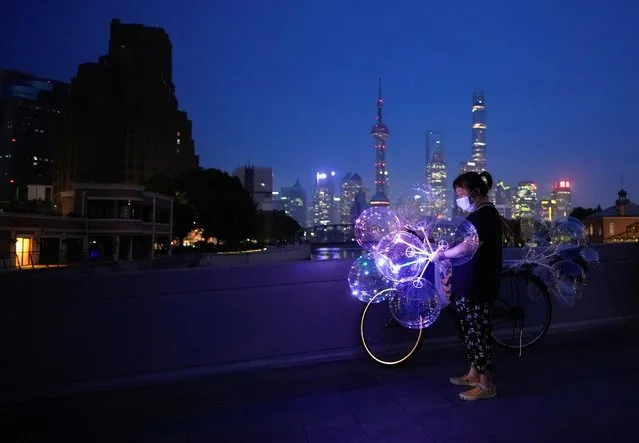 A woman sells balloons on a bridge near the Bund amid a heatwave warning, as Shanghai switches off lights along a popular waterfront to conserve energy in Shanghai, China on August 22, 2022. (Photo by Aly Song/Reuters)